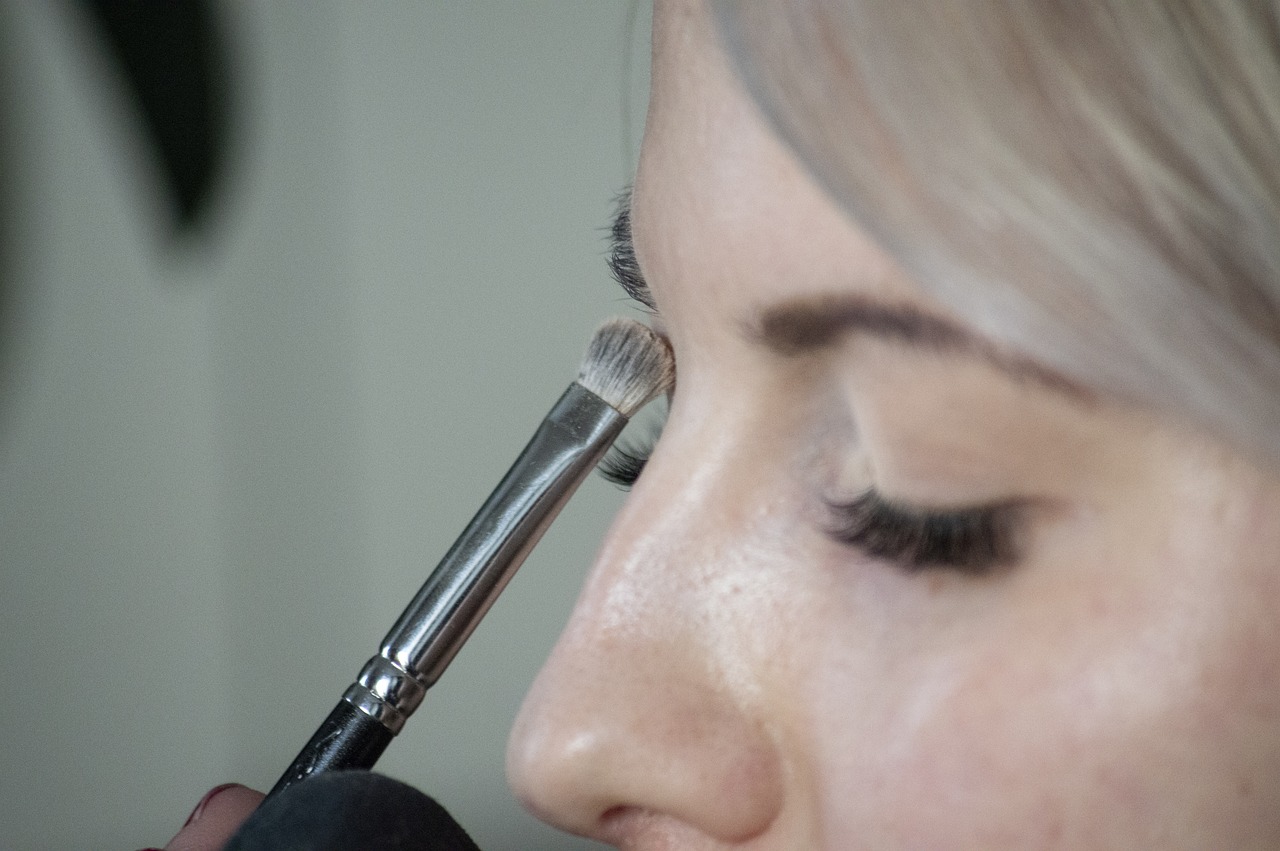 Blonde women using a makeup brush to apply eye shadow