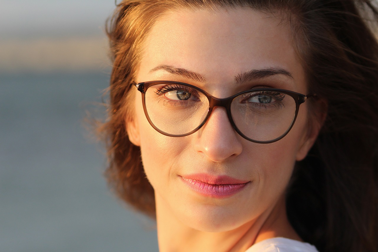 The image shows a close-up photograph of a woman with long, brown hair and wearing glasses