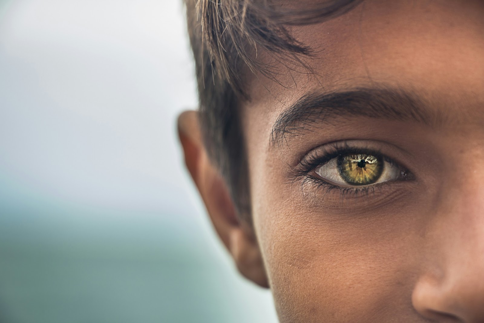 Close-up of person's face showing detailed view of golden-green eye and partial profile